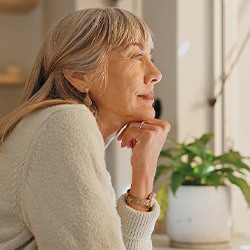 Senior woman smiling while looking out the window at home