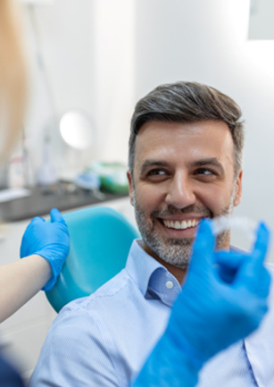 Patient smiling at dentist holding clear aligner