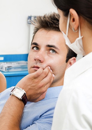 Man in dental chair holding cheek