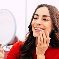 a patient checking her smile with a mirror