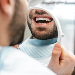 Patient smiling at reflection in handheld mirror