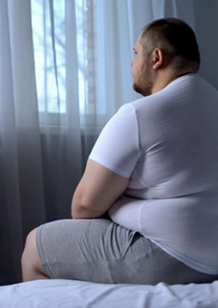 Overweight man sitting on a bed