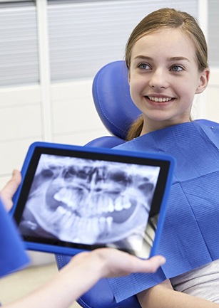 Smiling girl looking at dentist reviewing x-rays
