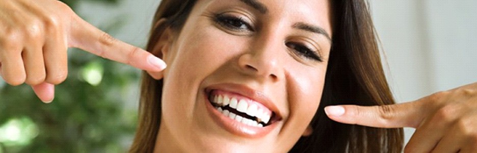 Woman smiling and pointing to her veneers in Cambria