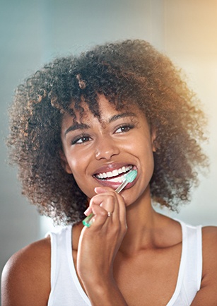 Woman smiling while brushing his teeth