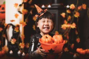 child holding a basket of pumpkins