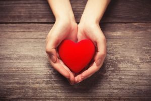 Cupped hands holding red heart shape without gum disease