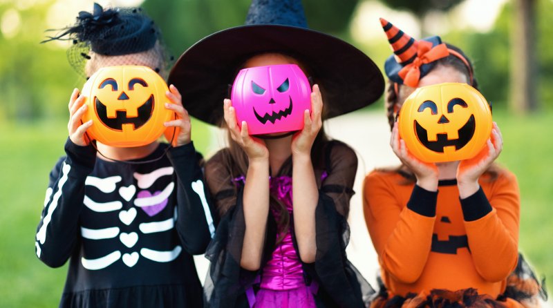 Children holding plastic pumpkins in their costumes