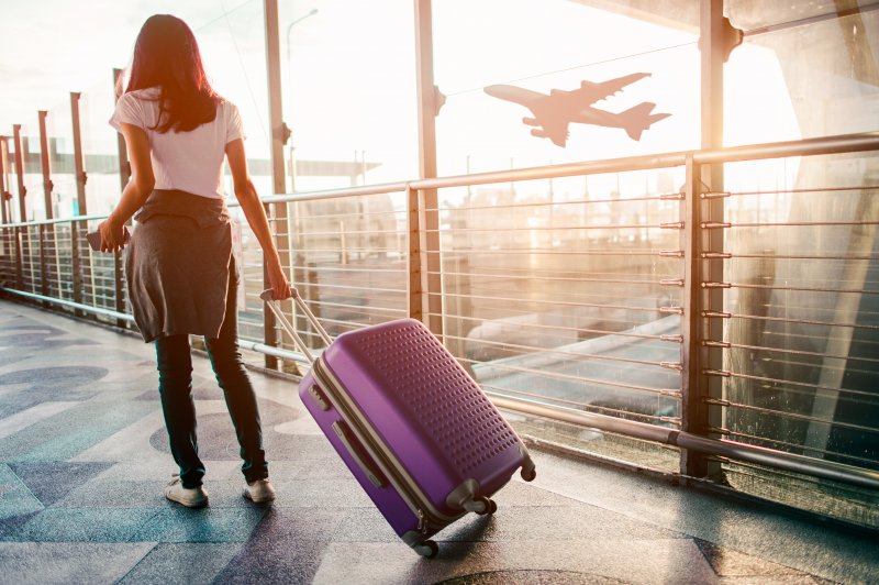 a woman pulling her luggage after planning to fly after a tooth extraction in Cambria