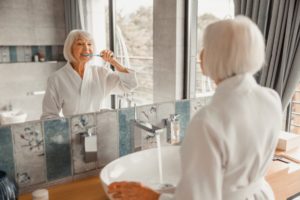 woman brushing teeth in mirror 