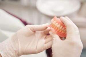 Closeup on gloved hands holding dentures.
